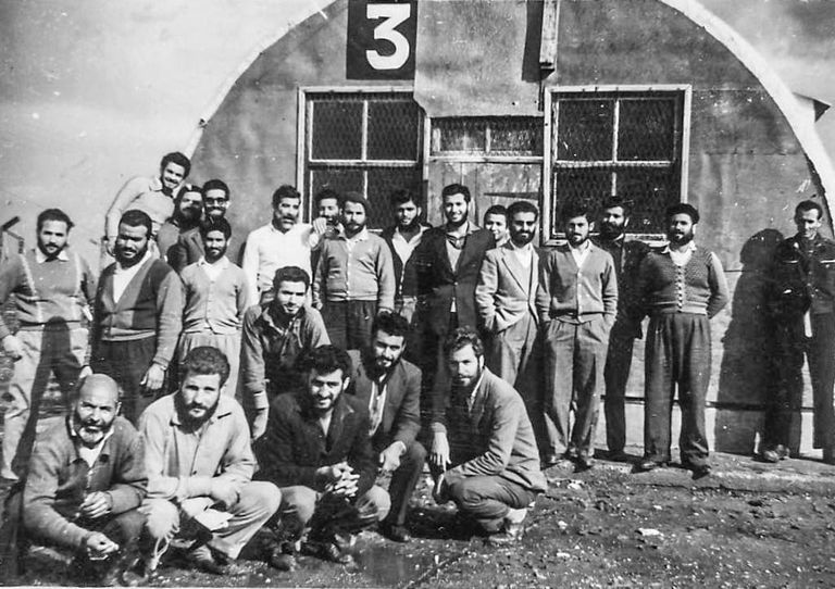 Fig. 15. Former detainees, posing by a Nissen Hut at  detention camp.